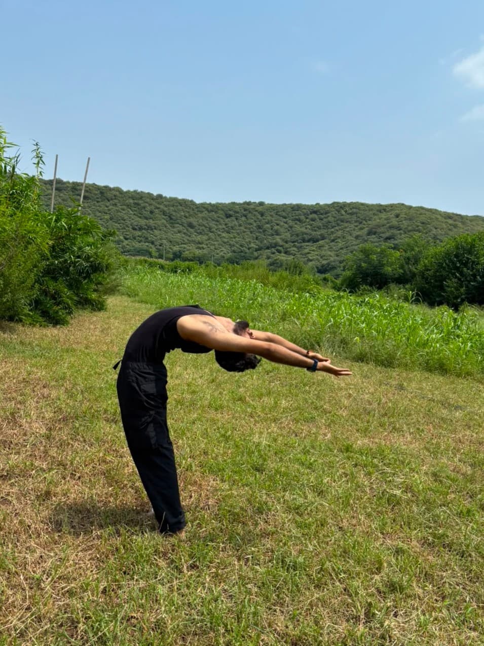 Aditya Pratap Singh in a standing backbend in a grassy field
