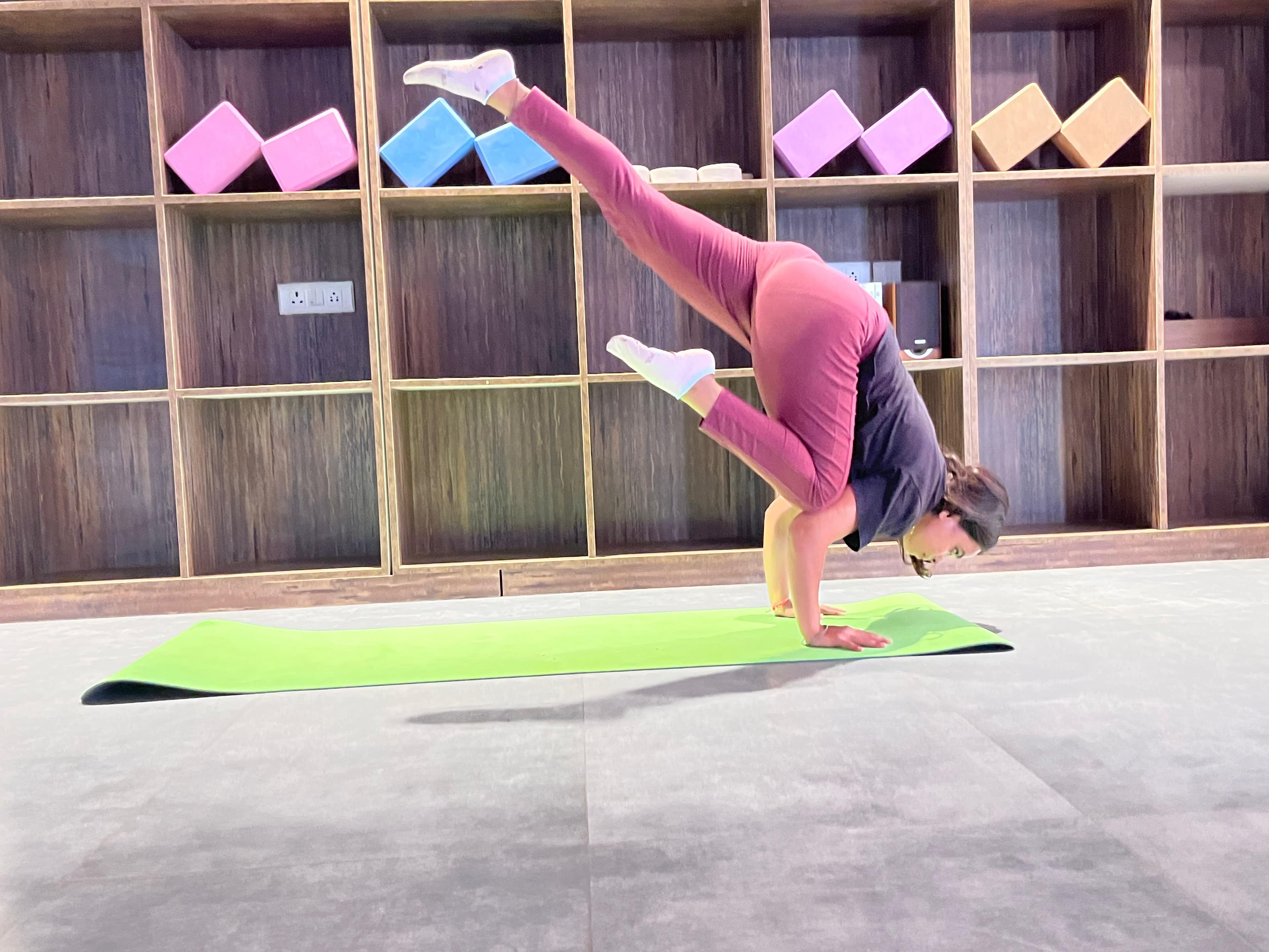 Shiya Shahi in an arm balance with her legs lifted in a yoga studio