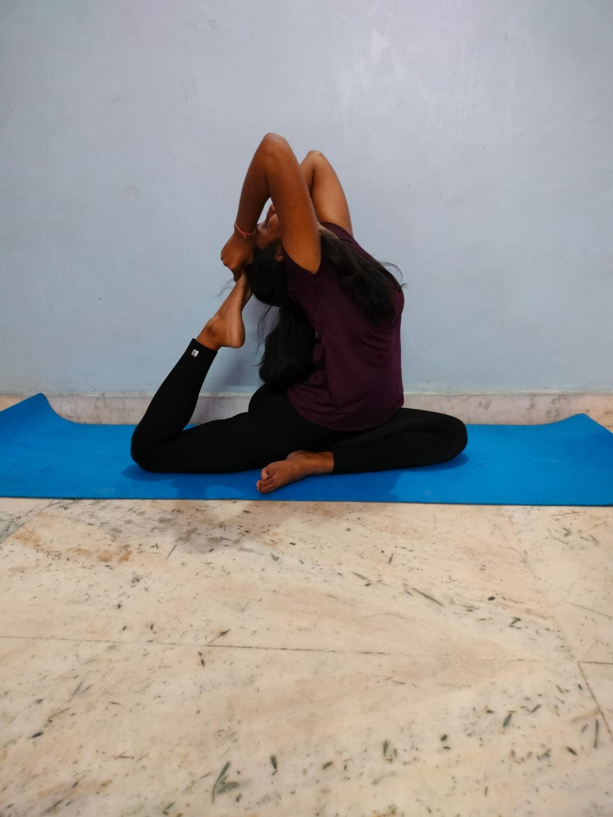 Pragya Devi in a seated yoga pose on a blue mat