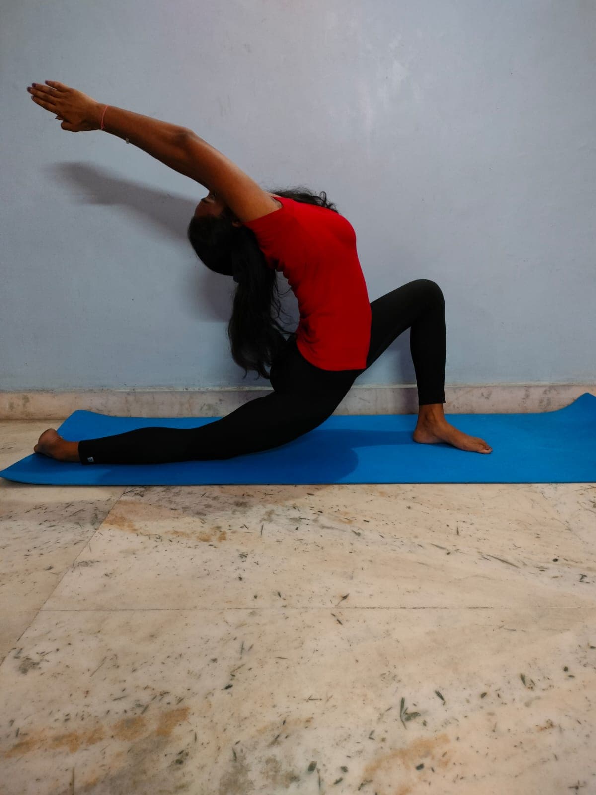 Pragya Devi in a low lunge with her arms raised